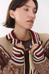 Cardigan de punto con diseño multicolor en tonos marrones, bordó y detalles en amarillo y celeste. Presenta cuello tipo polo, cierre frontal con botones, bolsillos aplicados en el frente y mangas con trama trenzada y coderas bordadas.