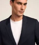 Blazer azul marino de tejido texturizado, con cuello solapa, abotonado delantero, mangas largas y bolsillos. Corte clásico.