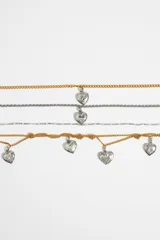 Collar de múltiples cadenas doradas y plateadas con dijes en forma de corazón con motivos grabados. Cierre de mosquetón.