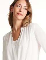 Blusa de gasa blanca, marca Catherine Malandrino, con cuello a la base y escote en V pronunciado. Incluye una pieza interna a tono para un escote discreto. Tiene manga larga con puño ancho y botón.