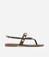 Sandalia marrón de cuero sintético, con tiras finas, apliques de conchas doradas y cierre con hebilla.