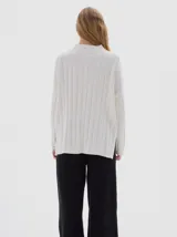 Buzo tejido de punto color beige, con cuello subido, diseño oversized y aberturas laterales en el ruedo.