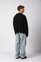 Sweater de punto liviano color negro con textura marcada, diseño de cuello redondo y calce holgado.