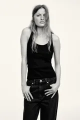 Jean wide leg de tiro alto en denim de algodón negro, con diseño de cinco bolsillos, perneras amplias y cierre frontal con botón y cremallera.