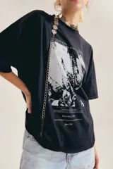 Remera oversize de algodón color blanco, con cuello redondo, mangas cortas y estampa gráfica frontal en blanco y negro con diseño vintage.