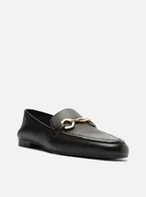 Mocasín de cuero negro con detalle de hebilla dorada.