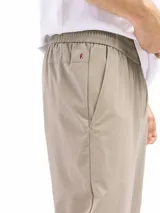 Pantalón casual color beige claro, de corte recto y tiro medio, con cintura elastizada y cordón ajustable. Presenta bolsillos laterales inclinados y costuras visibles en la parte delantera de las piernas.