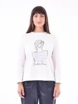 Remera de manga larga color crema con cuello redondo y un estampado central de un ramo de flores rosadas y naranjas en un jarrón azul oscuro.