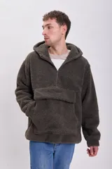 Buzo de hombre tipo canguro, confeccionado en tejido sherpa color visón. Tiene capucha, cierre parcial con cremallera y bolsillo tipo parche en el pecho.