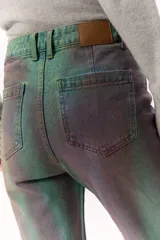 Pantalón de jean de tiro medio con estampado abstracto en tonos verdes y violetas.