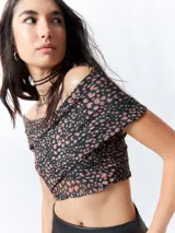 Top negro con estampado floral, escote off-shoulder, corte cruzado y mangas cortas.