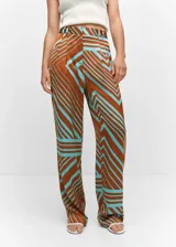 Pantalón de tiro medio con diseño recto y fluido, confeccionado en tejido satinado con estampado geométrico en tonos marrón y turquesa. Cuenta con cierre oculto de botón, gancho y cremallera, trabillas para cinturón, pinzas delanteras y dos bolsillos laterales.