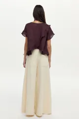 Blusa de lino color beige, de manga corta con volados, cuello redondo y espalda cruzada con volados.