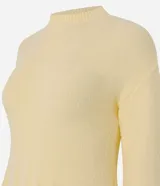 Suéter de tricot color amarillo claro, de manga larga y cuello redondo. Presenta detalles de volados acanalados en el ruedo y en los puños.