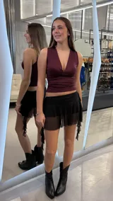 Minifalda negra con diseño de volados y transparencias, que incluye un short integrado debajo. Presenta un estilo de tiro bajo.