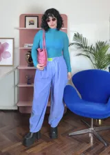 Pantalón de corte holgado y tiro alto, color celeste, confeccionado en poliéster. Presenta una cintura elástica con un aplique decorativo de acrílico en el frente y diseño de pinzas.