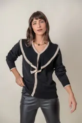 Cárdigan negro de punto fino con hilos de lurex, cuello en V calado con volados color crema, cierre frontal con botones con strass y puños anchos con ribete color crema.