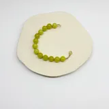Pulsera de cuentas esféricas de jade limón de 10 mm, con separadores de hilo verde y cierre de mosquetón con baño de oro.