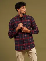 Camisa de franela a cuadros azules y grises, de manga larga con puños abotonados y dos bolsillos frontales con solapa abotonada.