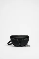 Bolso riñonera de cuero negro con textura granulada, tamaño mini. Cuenta con un compartimento principal con cierre de cremallera, dos bolsillos frontales con cierre, un asa de piel y una cadena metálica plateada. El exterior está personalizado con el logo de Bimba y Lola estampado.