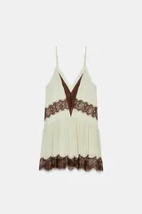 Vestido corto de tirantes finos ajustables con escote en pico. Presenta un diseño en color crema con detalles de encaje en color marrón a contraste en el escote, la cintura y el ruedo. Incluye forro interior.