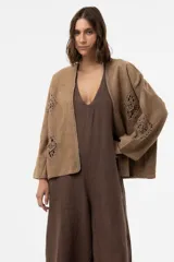 Chaqueta de gamuza color beige, con calce amplio y relajado, mangas anchas y detalles de inserciones de crochet con motivos florales.