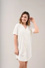Camisa de dormir o camisón de manga corta, color champagne, con cuello en V y abotonadura frontal. Presenta un bolsillo de parche en el pecho.
