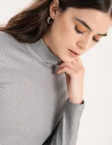 Polera gris de rib elastizado con brillos, cuello alto y mangas largas.