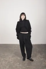 Pantalón de vestir negro, de corte amplio, con pliegues delanteros, bolsillos laterales y traseros.