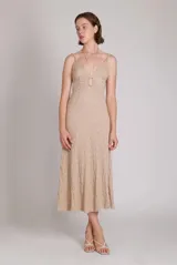 Vestido midi color beige con textura arrugada, escote en pico con abertura y lazos, tirantes finos ajustables y cierre de cremallera invisible en la espalda.
