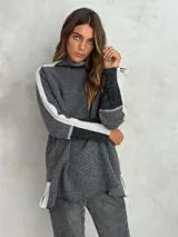 Sweater de punto con patrón de espiga en tonos beige y marrón, cuello alto, mangas largas con detalles en naranja y puños marrones.