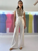 Mono largo color blanco, de lino con algodón, con bordado texturizado en los laterales superiores, cinto para ajustar en la cintura, cierre invisible central y bolsillos laterales.