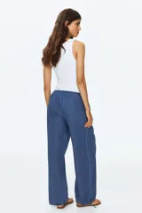 Pantalón de denim suave color azul, de corte holgado estilo globo con piernas abombadas, cintura elastizada con cordón ajustable y bajos con elástico y cintas para ajustar.