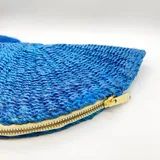 Bolso de mano azul tejido en abacá natural con forma de medialuna y cierre superior con cremallera.