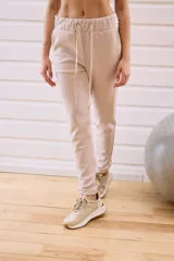 Babucha deportiva color beige con elástico en la cintura y puños, cordones regulables y bolsillos laterales.