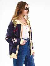 Campera tejida en jacquard con cierre frontal, cuello tipo polo y bolsillos delanteros. Diseño multicolor con estampado geométrico de rombos y detalles bordados a mano.