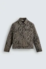 Cazadora de corte relajado confeccionada en tejido compacto con textura jacquard. Presenta cuello solapa, cierre frontal con cremallera, manga larga con puños ajustables mediante botones a presión, bolsillo con cierre en el pecho y bolsillos laterales de doble vivo.