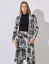 Cardigan largo de satén plisado con estampado abstracto en blanco y negro, marca Cyrus. Presenta aberturas laterales.