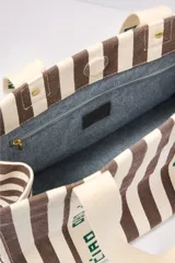 Bolso tote de lona a rayas verticales marrones y blancas con asas de mano y estampado "Ciao" en las asas.