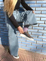 Zapatillas deportivas de cuero color peltre, con cordones negros y suela de goma blanca.