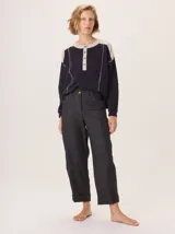 Pantalon de corte recto y tiro medio, confeccionado en tejido de lana con sutiles rayas verticales. Presenta bolsillos traseros aplicados, costuras reforzadas en las rodillas y ruedo con dobladillo.