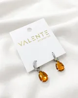 Aros colgantes plateados con dije de cristal facetado color ámbar en forma de lágrima.