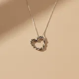 Collar de plata 925 con dije en forma de corazón con diseño trenzado y cadena de eslabones finos.