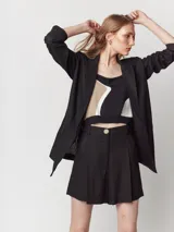 Short negro de lino de tiro alto con elástico en la pretina trasera, cierre delantero y botón. Presenta tablas en el frente, bolsillos delanteros y dobladillo invisible.