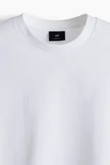 Remera blanca de algodón pesado, corte oversized, con cuello redondo ribeteado, hombros caídos y bajo recto.