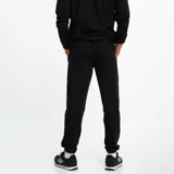 Pantalón de jogging negro con puños elásticos, cordón ajustable en la cintura, escudo del Club Atlético Peñarol bordado en amarillo y franjas laterales amarillas y grises.