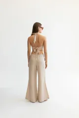 Pantalón color beige de lino, con elástico y tira ajustable en la cintura, bolsillos a ambos lados y pata de elefante estilo Oxford.