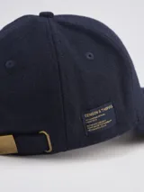 Gorra de béisbol de paño en color azul marino, con estructura de seis paneles y etiqueta pequeña con logo en el lateral.