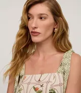 Vestido midi de corte evasé confeccionado en viscolino (mezcla de viscosa y lino). Presenta un diseño con estampado de palmeras y follaje sobre un fondo beige. Cuenta con escote cuadrado, breteles anchos con lazos ajustables en los hombros y espalda con lastex para un ajuste cómodo.