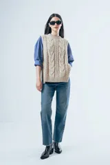 Chaleco de punto con diseño de ochos, cuello redondo y aberturas laterales con lazos ajustables.